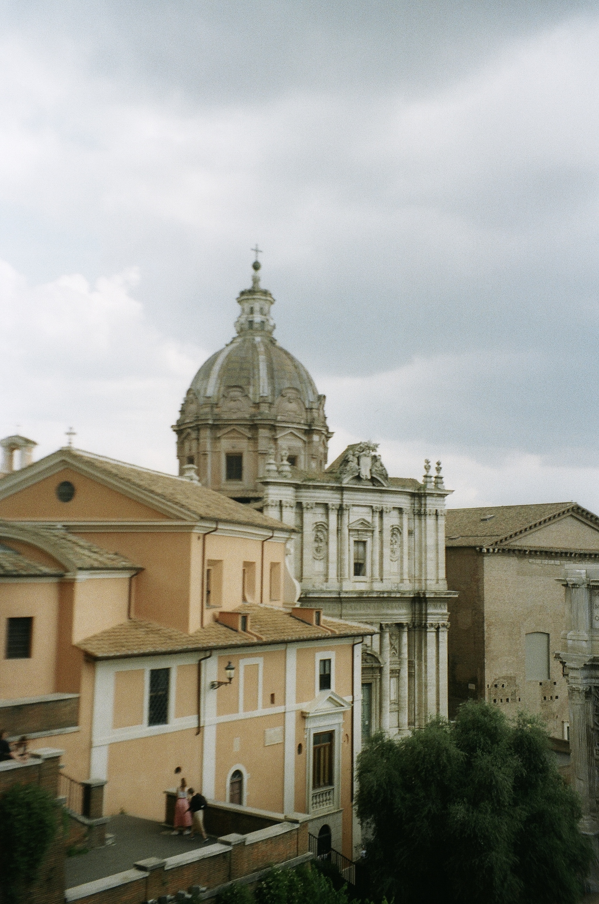 This is an image shot from a rooftop in Rome Italy, looking over some beautiful roftops and a very italian stone dome buildling.