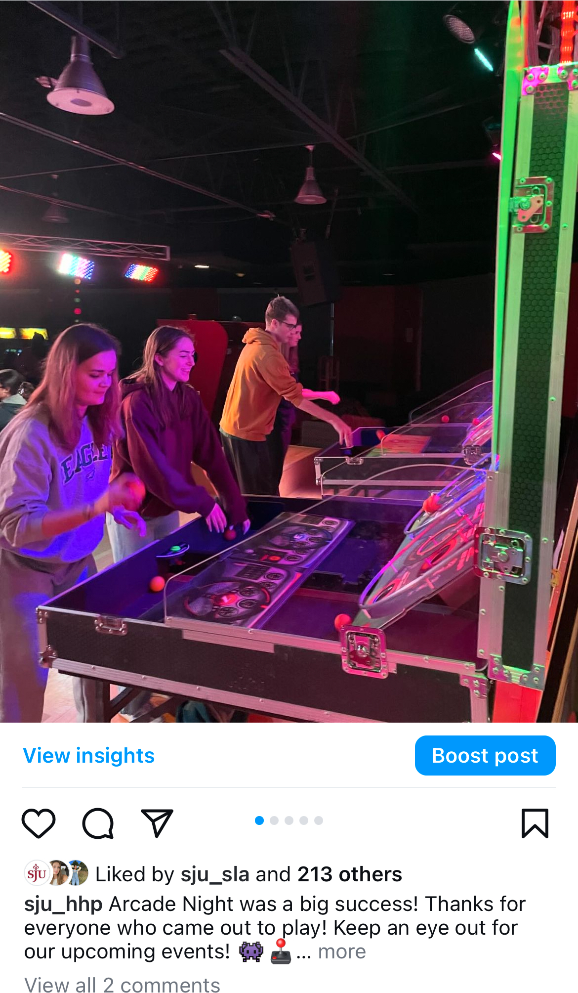 This image is a recap post from an arcade event for students. There are four students playing some kind of arcade game with neon lighting shining around them